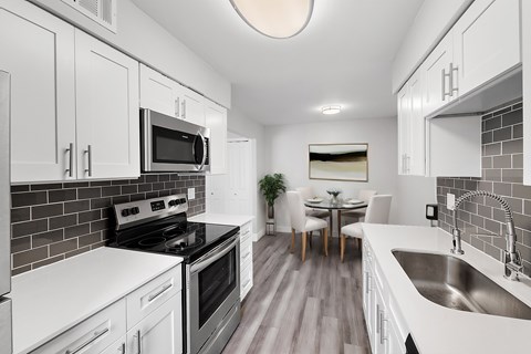 a kitchen with white cabinets and black appliances and a stainless steel sink